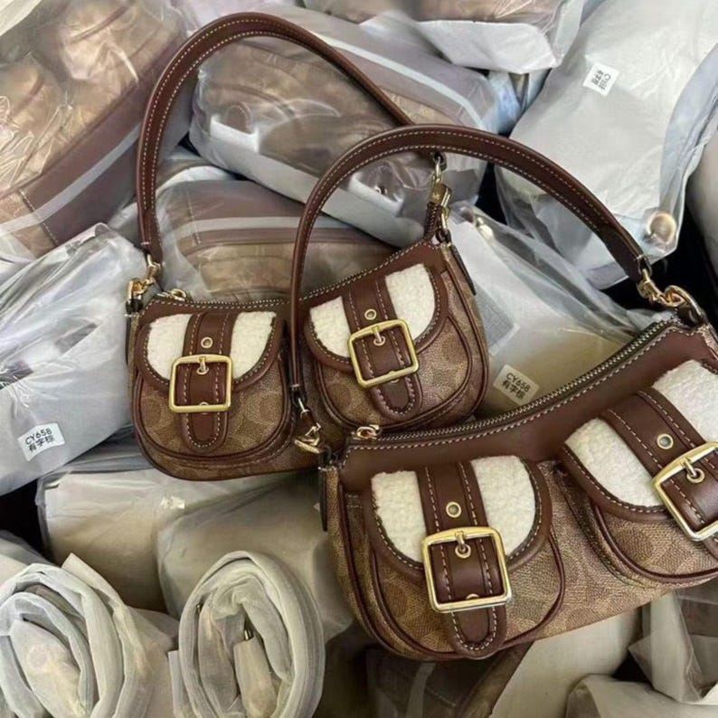 These are the Coach Ashton Shoulder Bags in signature jacquard and smooth leather, featuring distinctive front buckle pockets and detachable straps.