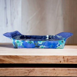 Può includere: Un copri teglia in tessuto con motivo floreale blu e bianco con manici. Il copri teglia è realizzato in tessuto ed è progettato per proteggere le mani dai piatti caldi.