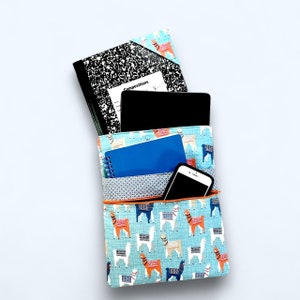 May include: A blue zippered pouch with a llama print design. The pouch is open and contains a black tablet, a blue spiral notebook, and a black smartphone.