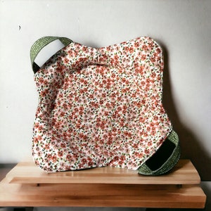 Könnte beinhalten: Ein grüner und weißer Stoffaufbewahrungskorb mit Henkel. Der Korb besteht aus einem weichen, gesteppten Stoff mit einem Blumenmuster. Der Korb ist perfekt zum Aufbewahren von kleinen Gegenständen wie Spielzeug, Decken oder Kleidung.