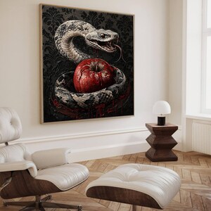 May include: A framed wall art print featuring a coiled grey and white snake with an open mouth and visible fangs, encircling a bright red apple. The background is a dark, ornate damask pattern with red liquid dripping from the apple and snake.