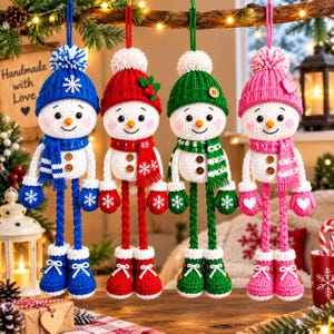 May include: Four crocheted snowman ornaments hanging by strings, each wearing a matching knit hat with a pom-pom, a scarf, and boots. The snowmen are colored blue, red, green, and pink, featuring embroidered faces, two buttons on their torsos, and mittens.