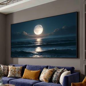 Può includere: Una grande stampa rettangolare da parete che raffigura una luna piena che brilla sopra un oceano scuro di notte. La scena mostra onde calme che riflettono la luce lunare sotto un cielo nuvoloso, incorniciata da un sottile bordo nero.