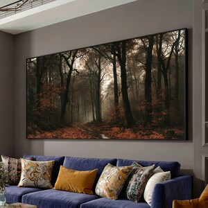 May include: A large rectangular wall art piece featuring a forest landscape with tall dark trees, a dirt path, and fallen orange leaves on the ground. The scene is captured in a moody, atmospheric light with soft illumination filtering through the branches.