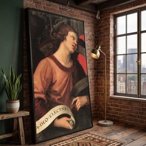 May include: A framed rectangular wall art print featuring a classical painting of a figure with wavy brown hair and a thin halo, wearing a reddish-orange tunic. The figure holds a scroll with the text A DEO ELECTVS in black capital letters.