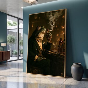 May include: A framed wall art print depicting an anthropomorphic frog dressed in a dark suit, waistcoat, and bowtie, sitting at a bar. The frog holds a lit cigarette with visible smoke rising, while a glass and a bottle are placed on the dark counter.