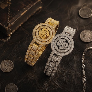 May include: Two wristwatches featuring a circular face with a prominent dollar sign symbol at the center, surrounded by clear crystals. One watch is gold-toned and the other is silver-toned, both with matching crystal-encrusted link bands.