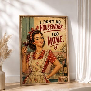 Puede incluir: Un cartel de pared rectangular con una ilustración de estilo vintage de una persona de cabello oscuro con un vestido rojo de lunares y un delantal floral, sosteniendo una copa de vino. El texto dice I DON'T DO HOUSEWORK... I DO WINE. con un corazón.
