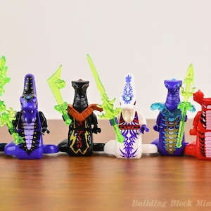 Puede incluir: Seis minifiguras de bloques de construcción con temática de serpiente en azul, morado, negro, blanco y rojo, cada una con una base de cola de serpiente y sosteniendo una espada de plástico verde neón translúcido. El texto Building Block Minifigures aparece.