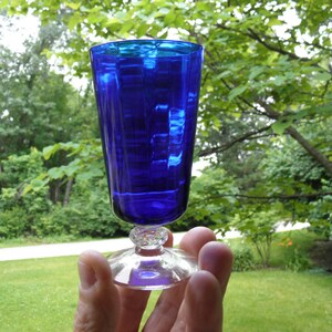 May include: A cobalt blue glass goblet with a clear glass stem and base. The goblet has a textured design.