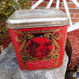 Puede incluir: Caja de hojalata vintage roja y dorada con diseño ornamentado y el texto "Ocean Blend Tea Co. Ltd. Perth Amboy, N.J. Trade Mark"
