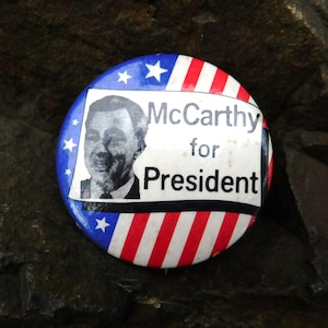 May include: A red, white, and blue button with a picture of a man and the text "McCarthy for President".