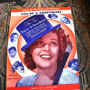 May include: A vintage sheet music cover for the musical "You're A Sweetheart" starring Alice Faye. The cover features a colorful illustration of Alice Faye in a blue and white hat, with the title of the musical in large, bold letters.