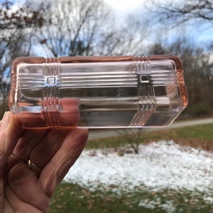 Peut inclure: Un plat rectangulaire en verre rose avec un motif géométrique en relief. Le plat est en verre transparent avec une teinte rose.