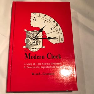 May include: A red book titled "The Modern Clock" with a clock face graphic. The cover features a partial clock face with Roman numerals and a diagram of clock gears. The text below reads "A Study of Time Keeping Mechanism: Its Construction, Regulation and Repair."