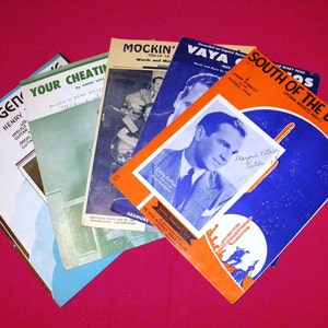 May include: Five vintage sheet music covers with blue, orange, and green backgrounds. The titles are "Sweet Genevieve", "Your Cheatin' Heart", "Mockin' Bird Hill", "Vaya Con Dios", and "South of the Border (Down Mexico Way)".