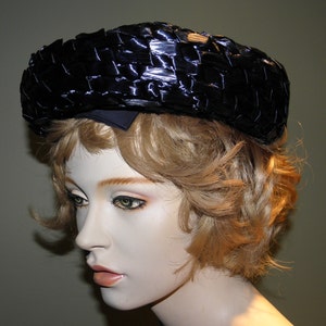 May include: A black woven hat with a wide brim. The hat is made of a shiny material and has a slightly rounded shape.