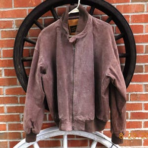 May include: A brown suede bomber jacket with a zipper closure. The jacket has a ribbed collar and cuffs.