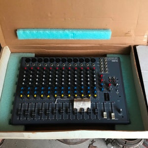 May include: A black 1602 XL audio mixer in its original box. The mixer has multiple knobs, sliders, and buttons. The box is brown with a blue foam insert.