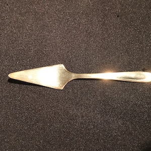 May include: A silver cake server with a pointed tip and a long, slender handle.
