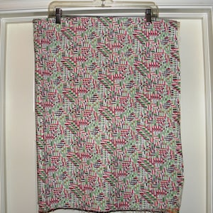 May include: A white fabric with a geometric pattern in red, green, black, and gray. The pattern is made up of small squares and rectangles.