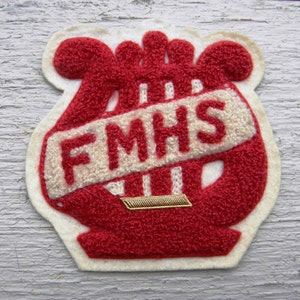 May include: Red felt patch with a white felt harp and the text "FMHS" in white felt.