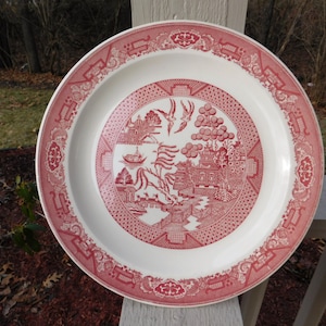 Puede incluir: Un plato de cena de cerámica rojo y blanco con un diseño de sauce. El plato tiene un fondo blanco con un sauce rojo, un puente rojo y pájaros rojos.