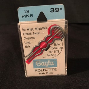 May include: A package of 18 silver Gayla HOLD-TITE hair pins. The package is blue and white and has a price tag of 39 cents. The hair pins are designed for wigs, wiglettes, French twists, chignons, and long hair. The package says "Note: Extra legs for TITE holding".