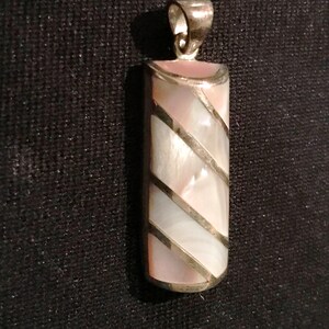 Puede incluir: Un colgante de plata con una incrustación rectangular de nácar. La incrustación tiene un patrón rayado de blanco y rosa.