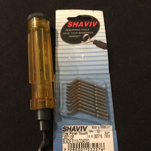 May include: A yellow and black deburring tool with a replaceable blade. The tool is made by Shaviv and is labeled "The Final Touch 3BE110P Blade E110 Coated". The package includes 10 blades.