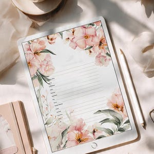 Può includere: Un tablet digitale che mostra un modello di cancelleria bianco con linee orizzontali e illustrazioni floreali rosa in stile acquerello negli angoli. Lo schermo presenta un elenco di voci di testo, circondato da una tazza di caffè e fiori.