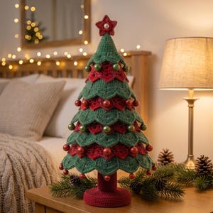 May include: A crocheted Christmas tree decoration featuring layered green and red scalloped fabric tiers. The tree is adorned with small, round, shiny red and green ornaments and is topped with a red crocheted star featuring a central white bead.