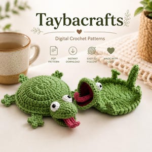 May include: Two green crocheted frog figures with white eyes and pink tongues. The text reads Taybacrafts Digital Crochet Patterns, PDF Pattern, Instant Download, Easy to Follow, Made with Love. The frogs are positioned near a ceramic mug.