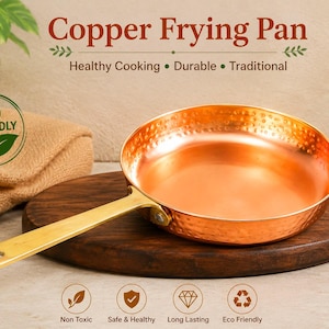May include: A round copper frying pan with a hammered exterior texture and a smooth, polished interior surface. The pan features a long, flat brass-colored handle attached with a single rivet. Text on the image reads Copper Frying Pan.