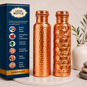 May include: Two cylindrical copper water bottles with metallic caps. One bottle features a hammered texture, while the other has a hexagonal honeycomb pattern. Beside them stands a tall blue box labeled COPPER BOTTLE with text listing six health benefits.