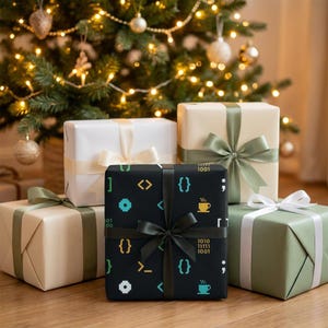 May include: Four gift boxes wrapped in paper. The central box is black with yellow, blue, and white programming symbols, coffee cups, and binary code, tied with a black ribbon. Other boxes are solid white, cream, and sage green with matching ribbons.