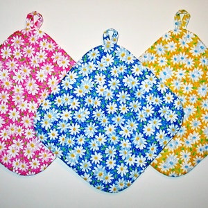 May include: Three pot holders with a daisy print. The pot holders are pink, blue, and yellow.