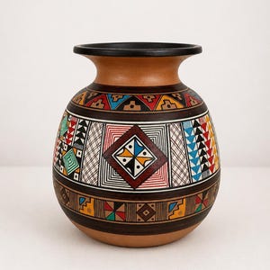 May include: A round ceramic vase with a wide neck and a black rim. The body features intricate geometric patterns in red, blue, yellow, black, and white, including diamonds, triangles, and cross-hatching on a terracotta-colored clay base.