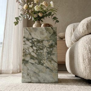 May include: A rectangular side table crafted from polished green and white marble with prominent veining. The table features a smooth, solid block construction and stands upright, serving as a base for a ceramic vase filled with flowers.