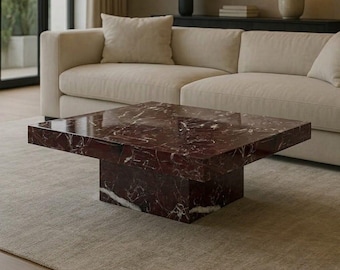 May include: A square coffee table crafted from deep red marble with prominent white veining. The table features a thick, flat tabletop surface supported by a solid, block-style pedestal base, showcasing a polished, reflective stone finish throughout.