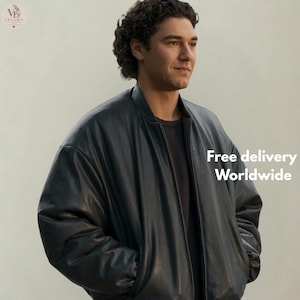 May include: A black bomber jacket with a smooth finish, featuring a ribbed collar, long sleeves, and a front zipper closure. The jacket is worn over a dark-colored shirt. The design includes a simple, clean silhouette with deep side pockets.