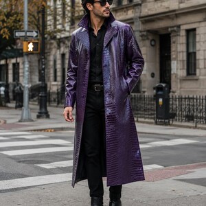 Può includere: Un lungo trench viola con una texture lucida in rilievo effetto pelle di coccodrillo, colletto ampio e chiusura con bottoni. Il cappotto è indossato sopra una camicia nera abbottonata, pantaloni neri, una cintura nera e stivaletti in pelle.
