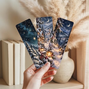 May include: Three rectangular bookmarks featuring winter night scenes. The left shows a starry sky over snow-covered pine trees. The center and right bookmarks depict a snowy path, glowing lanterns, decorated evergreen trees, and a crescent moon.