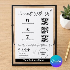 Puede incluir: Un marco de metal negro que sostiene un letrero blanco con el texto Connect With Us, iconos de redes sociales, códigos QR y espacios para un logotipo y nombre de empresa. El letrero incluye datos de contacto y Follow US on Social Media.