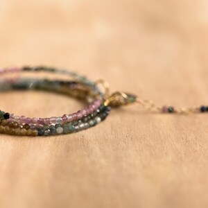Pu&ograve; includere: Un braccialetto a pi&ugrave; fili con piccole perline colorate nelle tonalit&agrave; del rosa, verde e oro. Il braccialetto ha una delicata catena e chiusura dorata. Le perline sono infilate per creare un effetto a strati, perfetto per l'uso quotidiano.