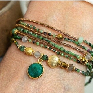 May include: A multi-strand bracelet with green and brown beads, gold accents, and a large green gemstone pendant.