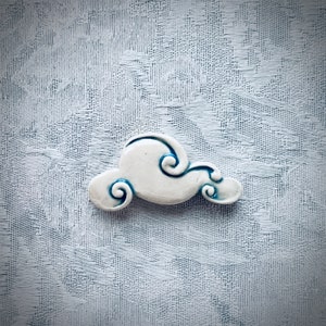 May include: White ceramic cloud with blue swirl details. The cloud is a decorative object.