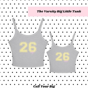 Könnte beinhalten: Zwei graue Tanktops mit dünnen Trägern, die jeweils die Zahl 26 in einer hellgelben Schriftart im Varsity-Stil zeigen. Das größere Tanktop hat das Wort Big in kleiner rosa Schreibschrift unter der Zahl, das kleinere das Wort Little in Rosa.
