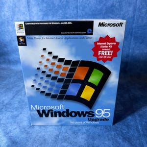 May include: A Microsoft Windows 95 Upgrade software box featuring the iconic multi-colored window logo against a blue sky background. The packaging includes text such as More Power for Internet Access, Applications, and Games and a red starburst graphic.