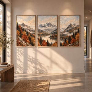 May include: A set of three framed vertical wall art prints depicting a continuous mountain landscape scene with a lake, evergreen trees, and autumn foliage in shades of orange, yellow, and green under a soft, cloudy sky with light blue tones.